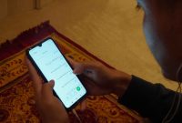 Usai shalat, seorang muslim membaca dan mendengarkan maulid melalui aplikasi Kesan. Foto: Istimewa 