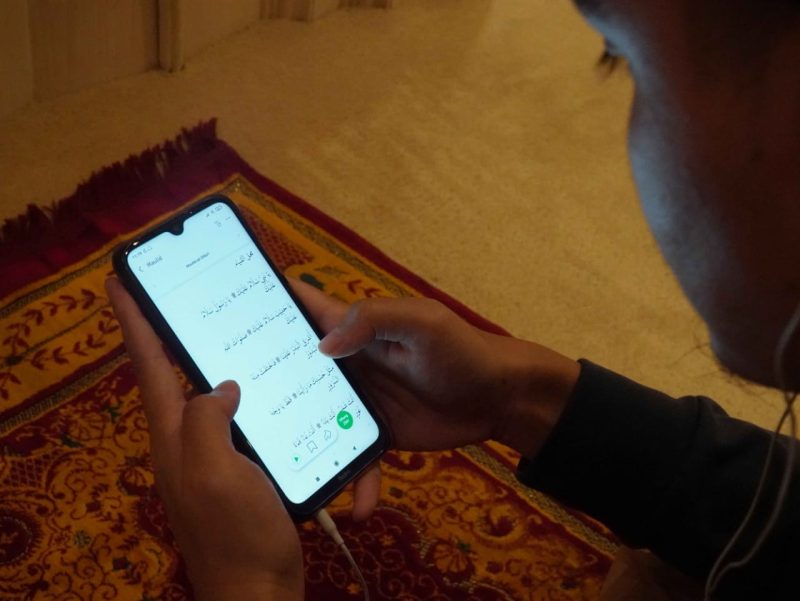 Usai shalat, seorang muslim membaca dan mendengarkan maulid melalui aplikasi Kesan. Foto: Istimewa 