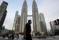 Pejalan kaki berjalan di depan menara Petronas, Kuala Lumpur, Malaysia. Foto: Reuters 