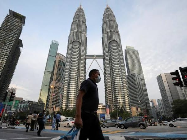 Pejalan kaki berjalan di depan menara Petronas, Kuala Lumpur, Malaysia. Foto: Reuters 