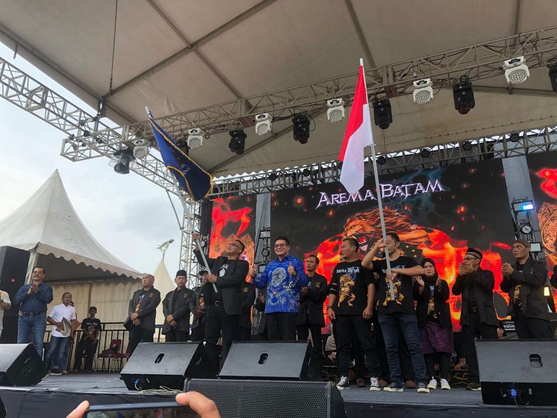 Ketua Paguyuban Keluarga Besar Arema Batam (PKBAB) Kota Batam Teguh Dia Mafianto, mengibarkan bendera pataka. Foto: INIKEPRI.COM 