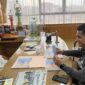 Di antara tumpukan berkas dan tropi-tropi yang berdiri sunyi, dua manusia berbagi senyap yang bermakna. Wali Kota Amsakar menunduk dalam jeda, sementara saya membaca secarik harapan yang terlipat rapi dalam lembaran dokumen. Di ruang ini, waktu seakan melambat—sebab tidak semua pertemuan perlu suara untuk menjadi berarti. 