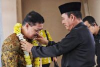 Gubernur Kepri Ansar Ahmad mengalungkan karangan bunga kepada Jehezkiel Devy Sudarso, Kajati Kepri yang baru di Bandara Raja Haji Fisabilillah Tanjungpinang, Jumat (18/7/2025). Foto: INIKEPRI.COM/Diskominfo Kepri