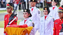 Tsaniyah Aqillah Muca I Kadek membawa replika Sangska Merah Putih yang diserahkan Gubernur Kepri Ansar Ahmad dalam upacara Peringatan HUT RI ke-80 Tingkat Provinsi Kepri di Gedung Daerah, Minggu (17/8/2025). Foto: INIKEPRI.COM/KepriProv 
