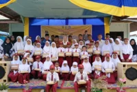 Bupati Natuna Cen Sui Lan berfoto bersama para siswa SD di Kecamatan Midai usai menyerahkan bantuan perlengkapan belajar pada kunjungan kerjanya. Foto: Istimewa 