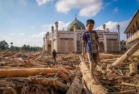 Seorang anak berjalan di depan masjid pasca bencana banjir bandang. Foto: BBC