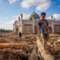 Seorang anak berjalan di depan masjid pasca bencana banjir bandang. Foto: BBC