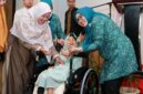 Ketua TP-PKK Batam, Erlita Amsakar, menyerahkan kursi roda kepada salah seorang penerima. Foto: INIKEPRI.COM