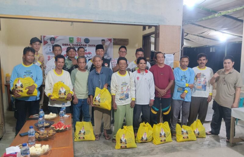 Warga Desa Harapan Jaya, Kecamatan Bunguran Tengah, berfoto bersama usai menerima paket sembako dari Yayasan KPDN dalam rangkaian pembukaan Turnamen Domino KPDN, Sabtu (8/8/2026) malam. Foto: INIKEPRI.COM